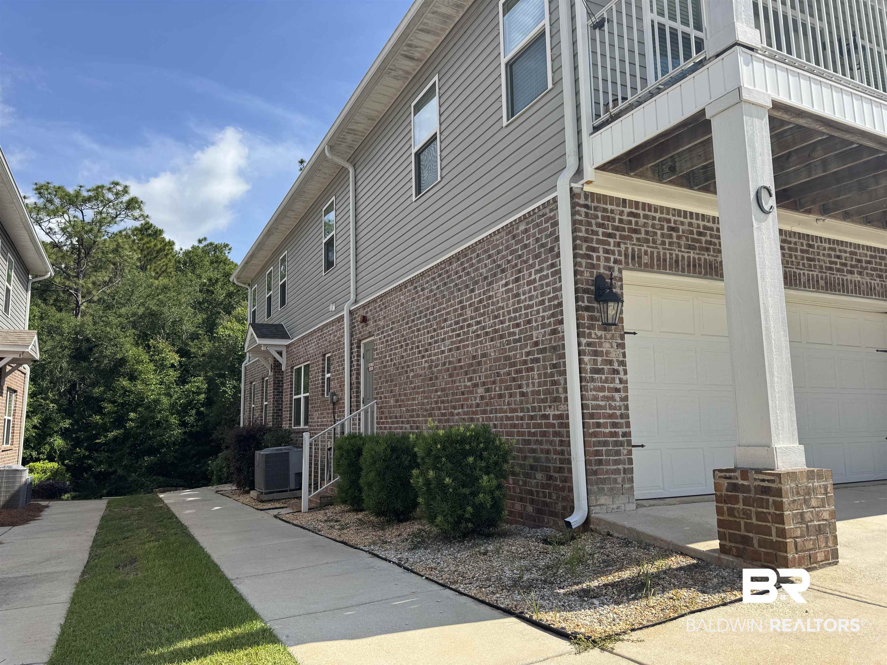 6811 Spaniel Drive, Unit C Daphne, AL 36527 - Photo 29 of 33 View of home's exterior with brick siding, a balcony, a garage, and central AC unit