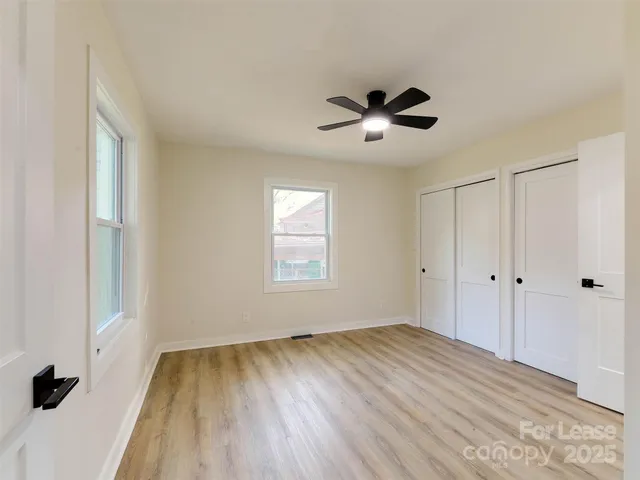 a view of empty room with wooden floor and fan