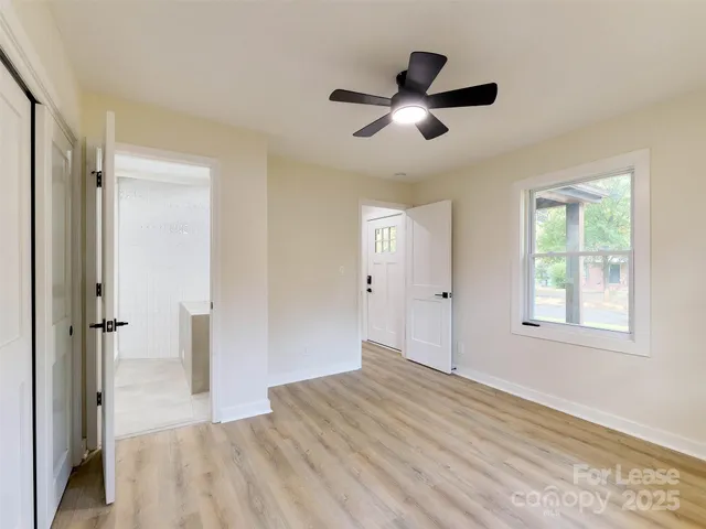 a view of empty room with wooden floor and fan