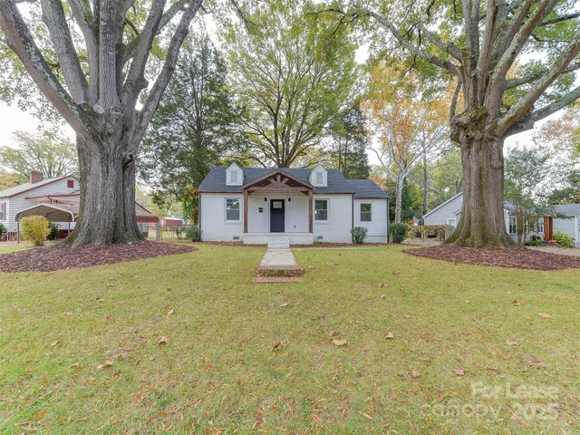 a front view of a house with yard and tree