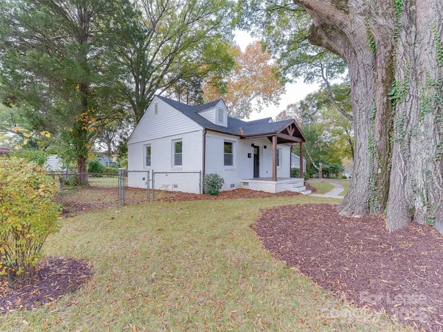 a front view of a house with a garden and trees