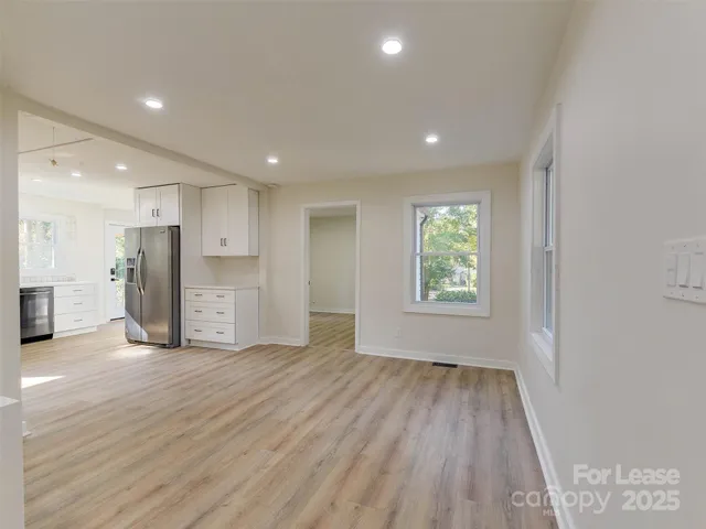 a view of an empty room with a window and wooden floor