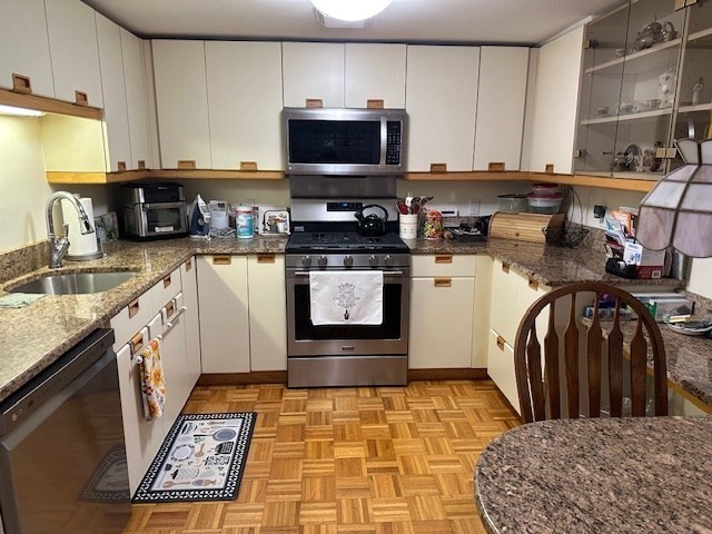 166 Place Lane, Unit 166 Woburn, MA 01801 - Photo 2 of 26 a kitchen with stainless steel appliances granite countertop a stove a sink and a microwave