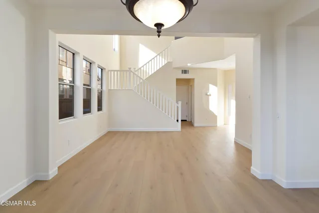 a view of a big room with wooden floor and windows