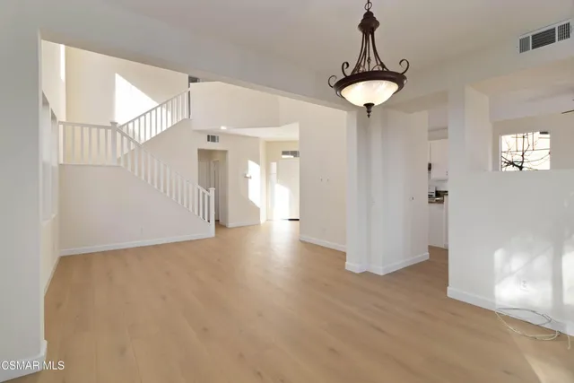 a view of a hallway with wooden floor and a chandelier