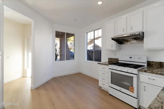 a kitchen with stainless steel appliances white cabinets and a stove top oven