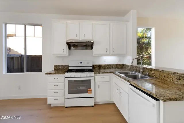 a kitchen with granite countertop white cabinets and white appliances