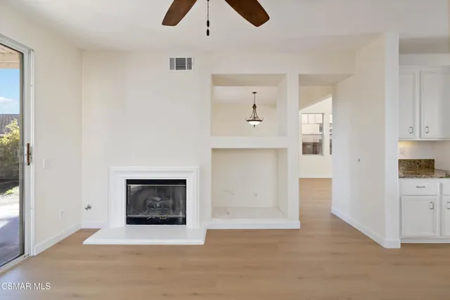 a view of kitchen and empty room with cabinet