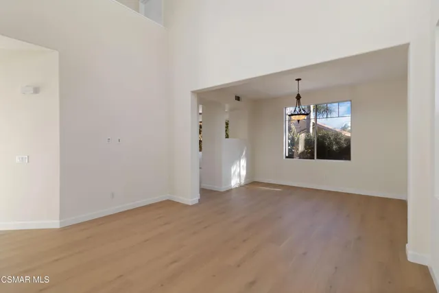 a view of an empty room with window and wooden floor