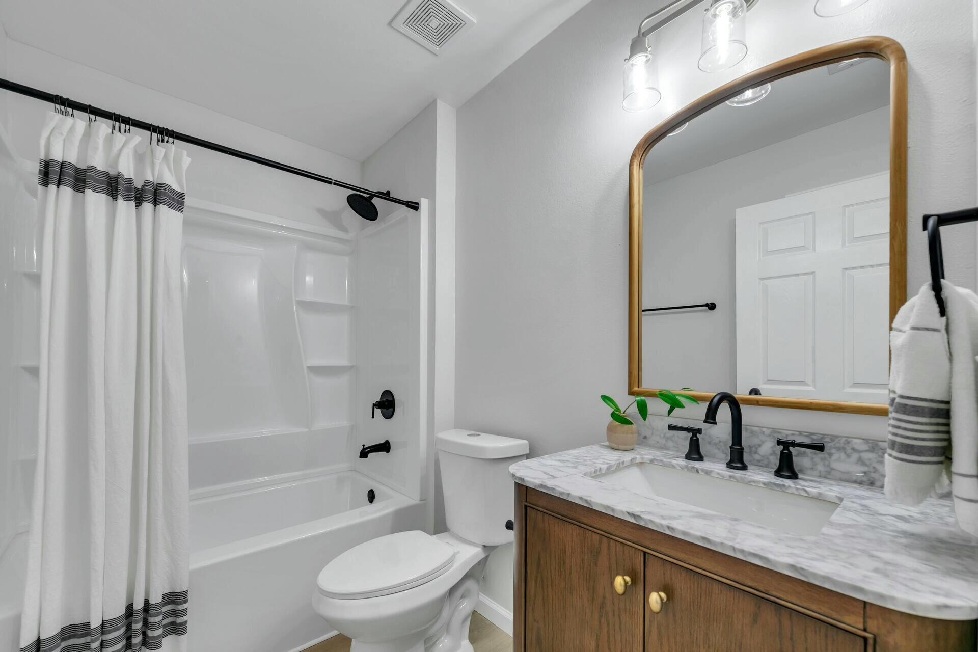 330 Apple Drive Crestview, FL 32536 - Photo 12 of 29 a bathroom with a granite countertop sink toilet a large mirror a bathtub and shower