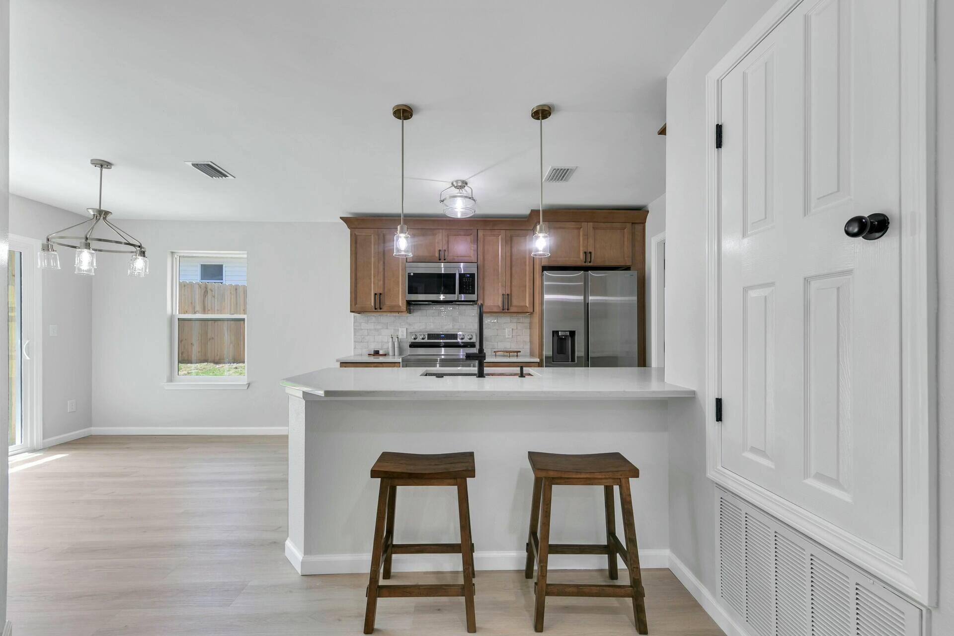 330 Apple Drive Crestview, FL 32536 - Photo 2 of 29 a kitchen with kitchen island a sink stove and refrigerator with wooden floor