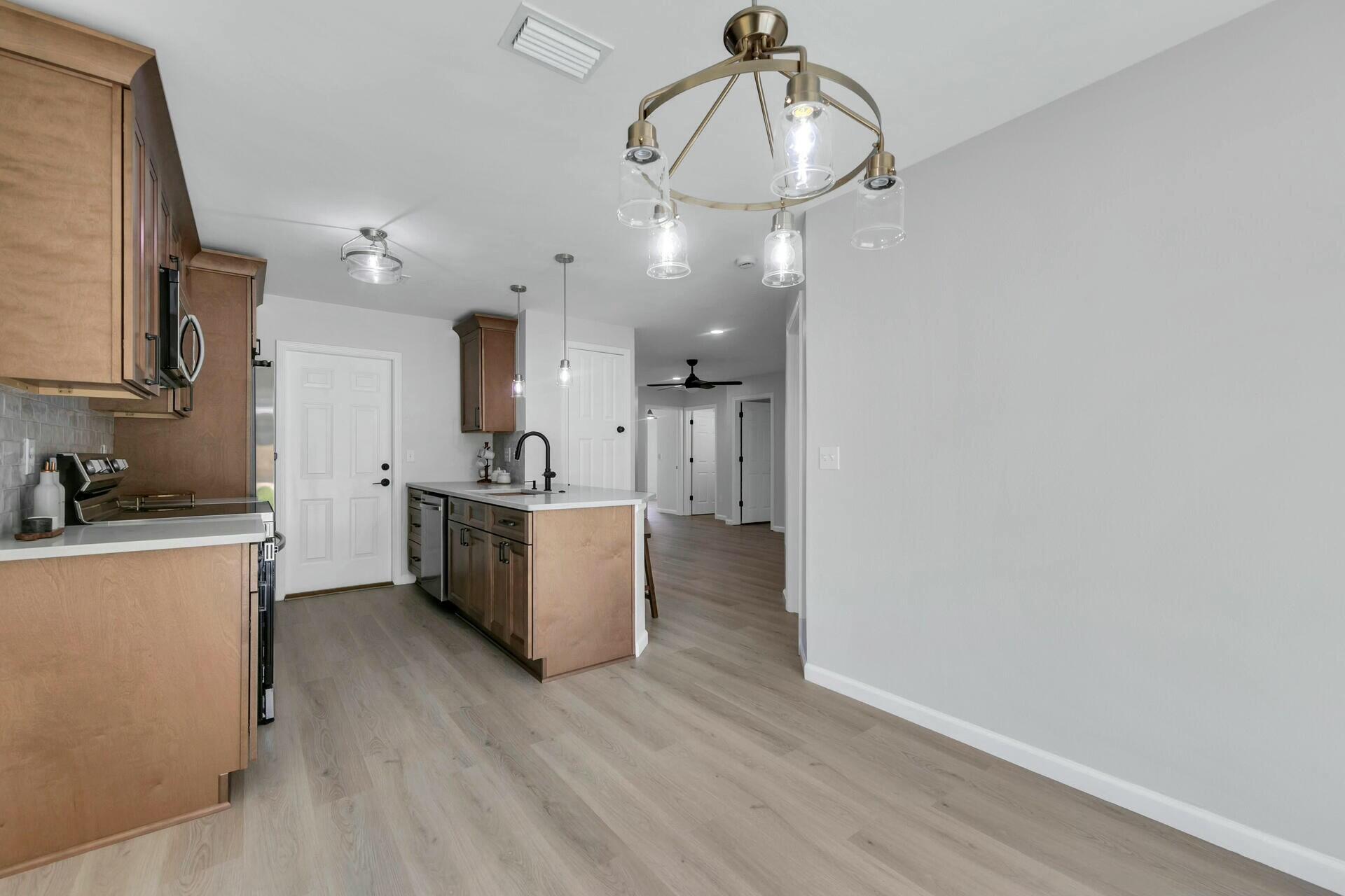 330 Apple Drive Crestview, FL 32536 - Photo 6 of 29 a view of a kitchen with a sink and dishwasher a refrigerator with wooden floor