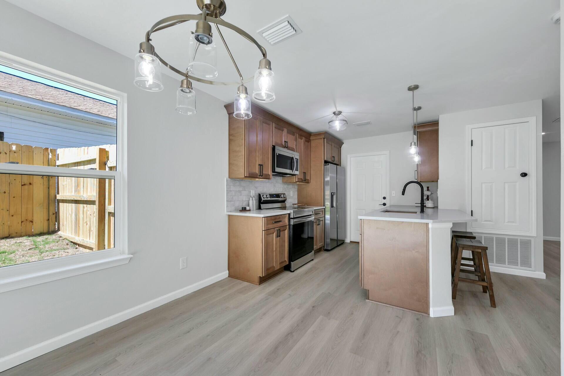 330 Apple Drive Crestview, FL 32536 - Photo 7 of 29 a kitchen with kitchen island a sink cabinets and wooden floor