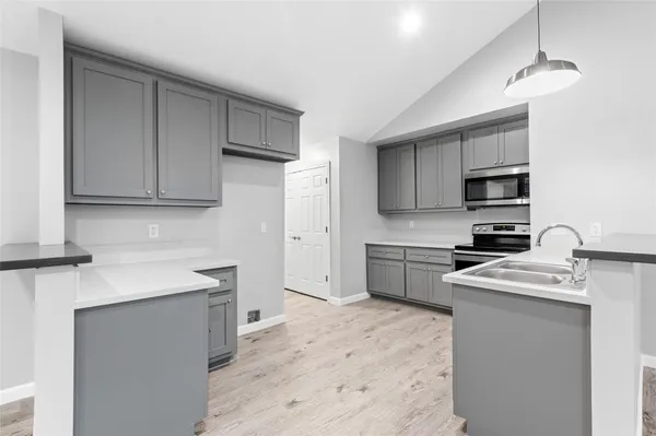 a kitchen with stainless steel appliances granite countertop a sink stove a refrigerator a microwave oven with white cabinets
