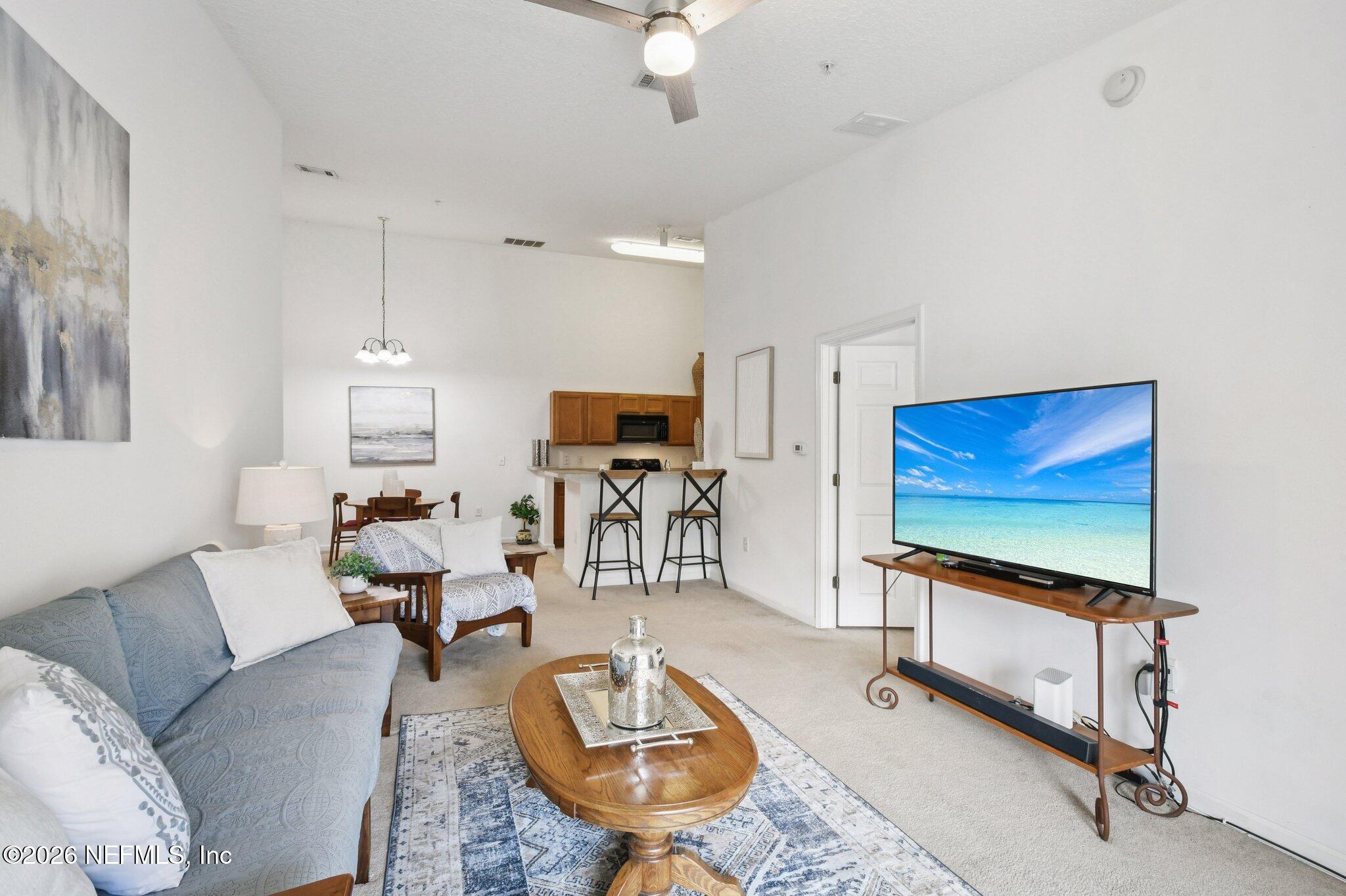 7920 Merrill Road, Unit 1114 Jacksonville, FL 32277 - Photo 10 of 31 a living room with furniture a flat screen tv and a floor to ceiling window