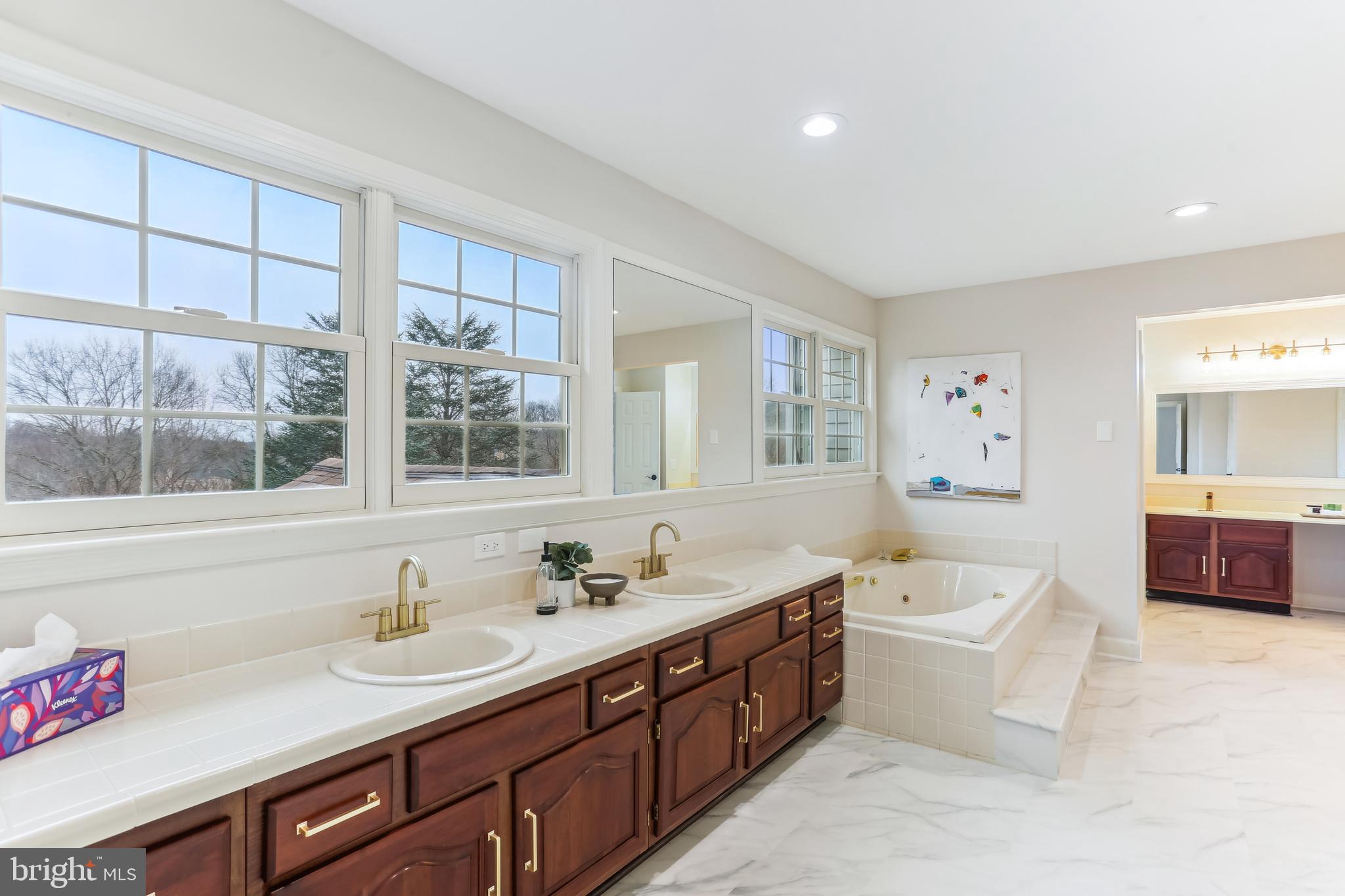 9409 Thornedike Drive Laytonsville, MD 20882 - Photo 43 of 86 a spacious bathroom with a double vanity sink a mirror and a bathtub