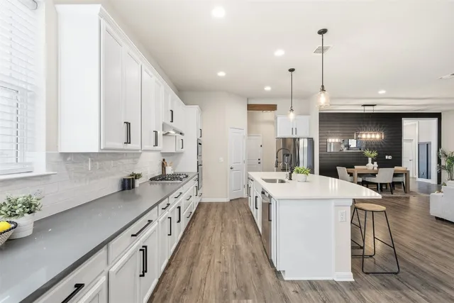 a kitchen with stainless steel appliances granite countertop a stove a sink and white cabinets