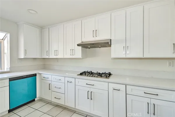 a kitchen with white cabinets and stove