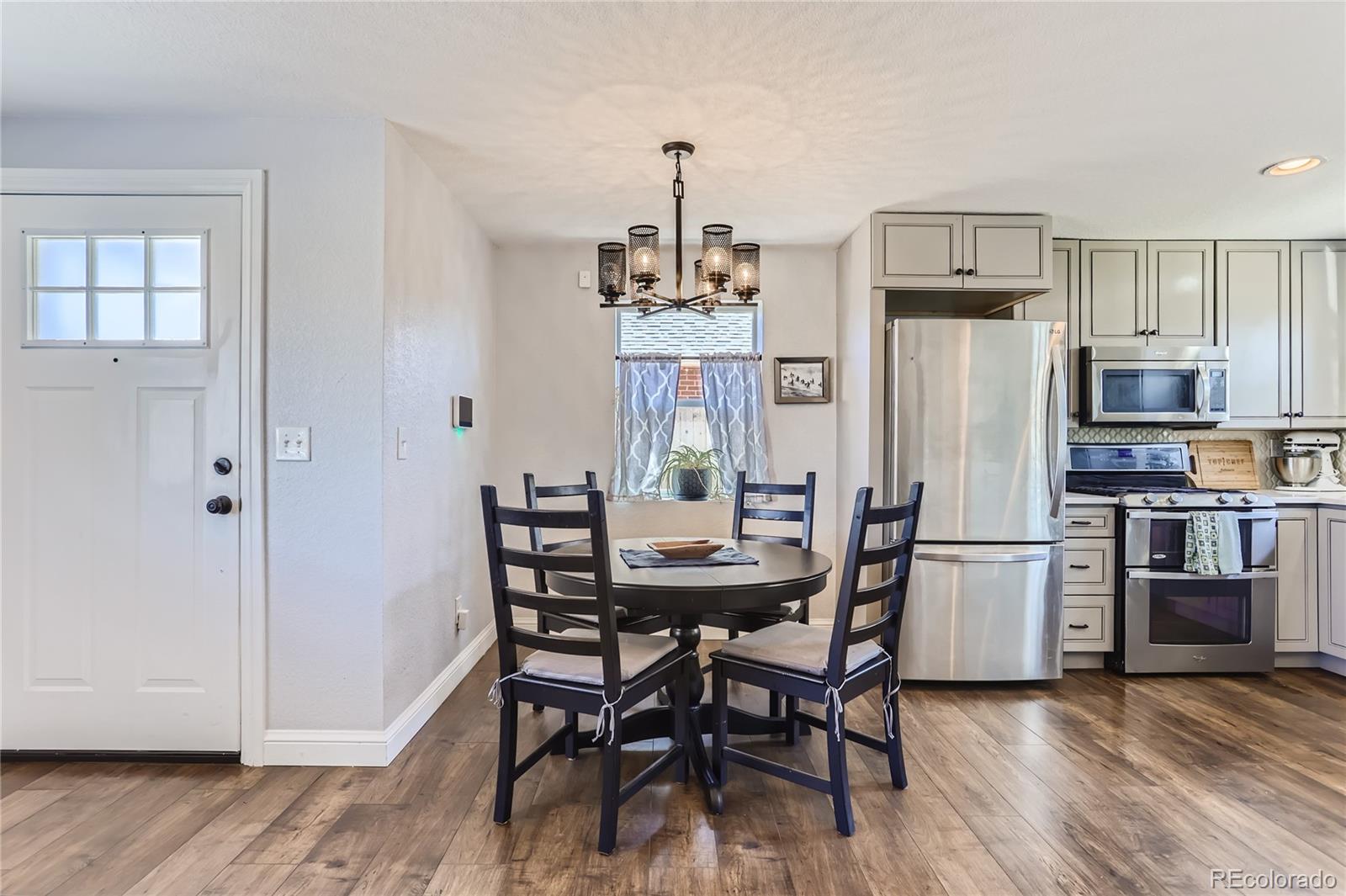 3051 Grape Street Denver, CO 80207 - Photo 2 of 33 a kitchen with stainless steel appliances a dining table chairs refrigerator and microwave