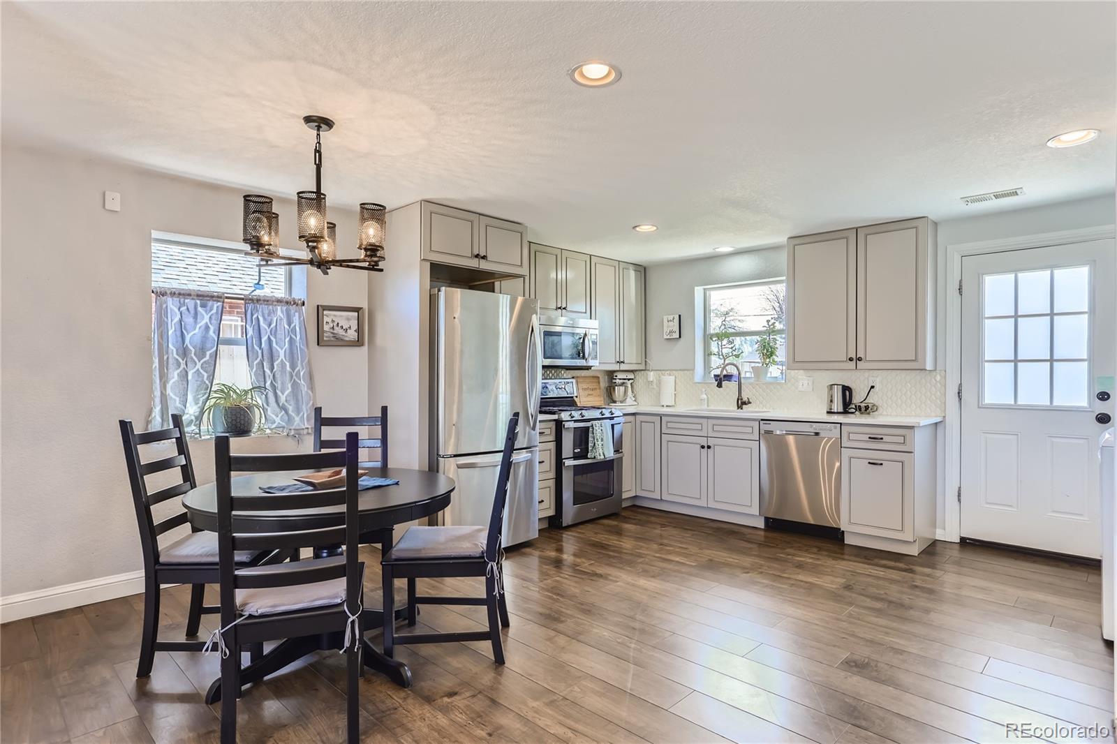 3051 Grape Street Denver, CO 80207 - Photo 8 of 33 a kitchen with a table chairs wooden floors and white stainless steel appliances