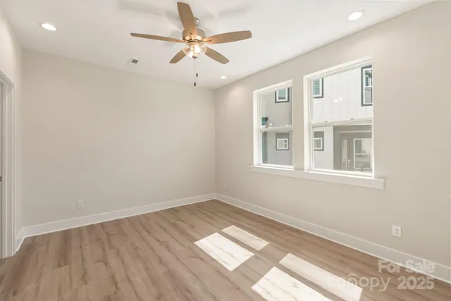 a view of an empty room with a window and wooden floor