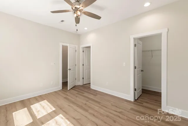 an empty room with wooden floor and ceiling fan