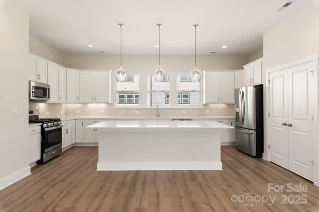 a kitchen with kitchen island a counter top space a sink stainless steel appliances and cabinets