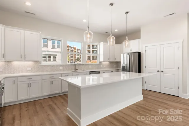 a kitchen with stainless steel appliances granite countertop a sink a stove a refrigerator and island with wooden floor