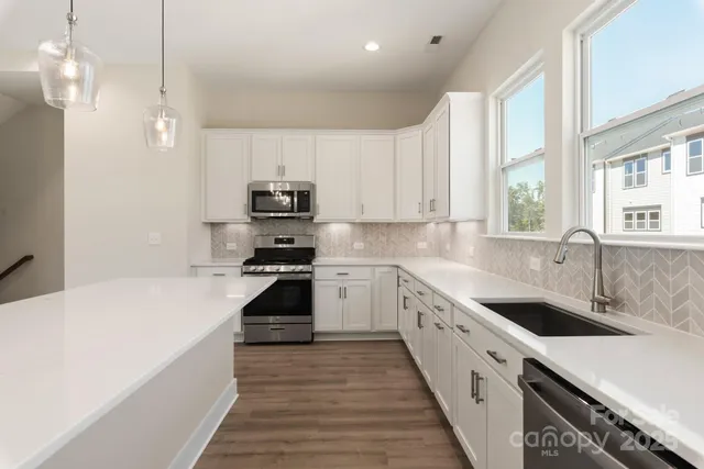 a kitchen with granite countertop a sink a counter space appliances and cabinets