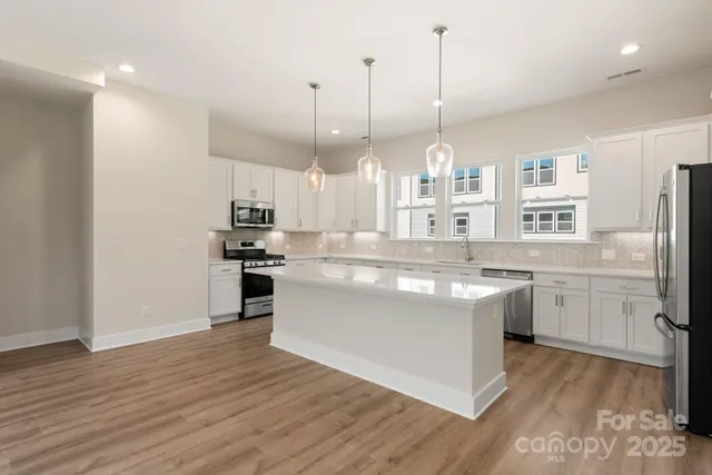 a kitchen with kitchen island granite countertop a sink cabinets and wooden floor