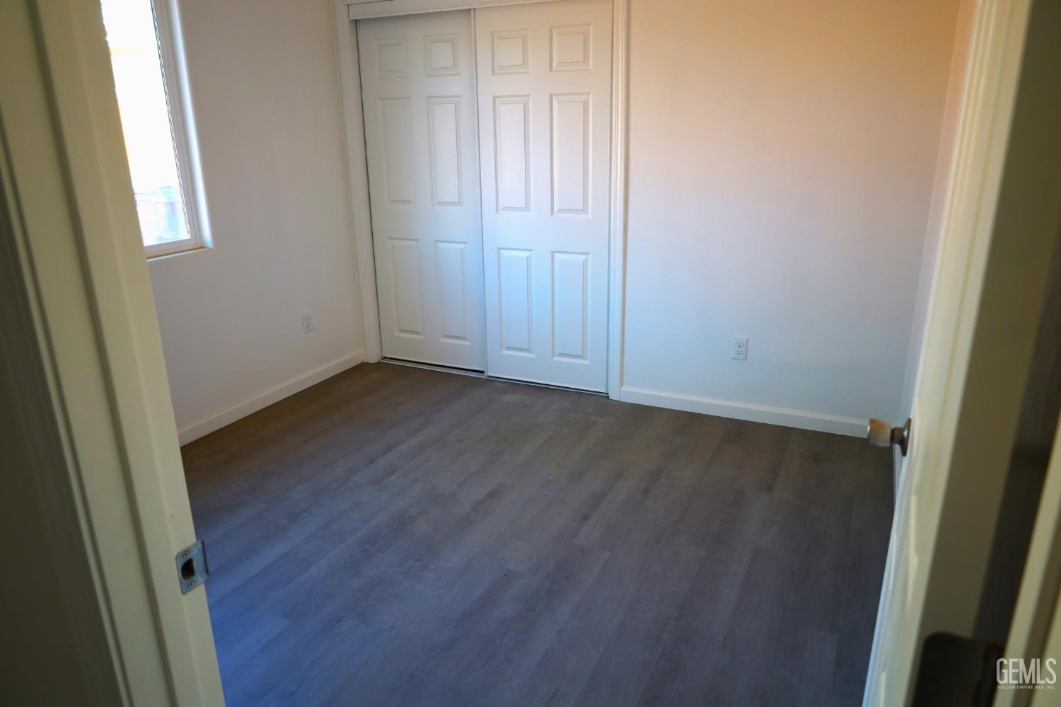 Undisclosed Address Bakersfield, CA 93307 - Photo 5 of 12 an empty room with wooden floor and windows