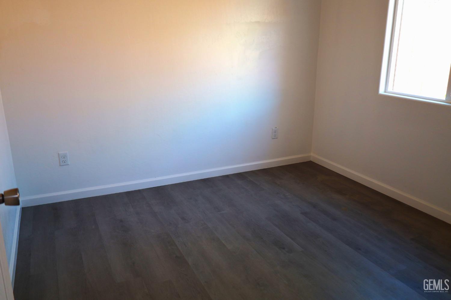 Undisclosed Address Bakersfield, CA 93307 - Photo 10 of 12 an empty room with wooden floor and windows