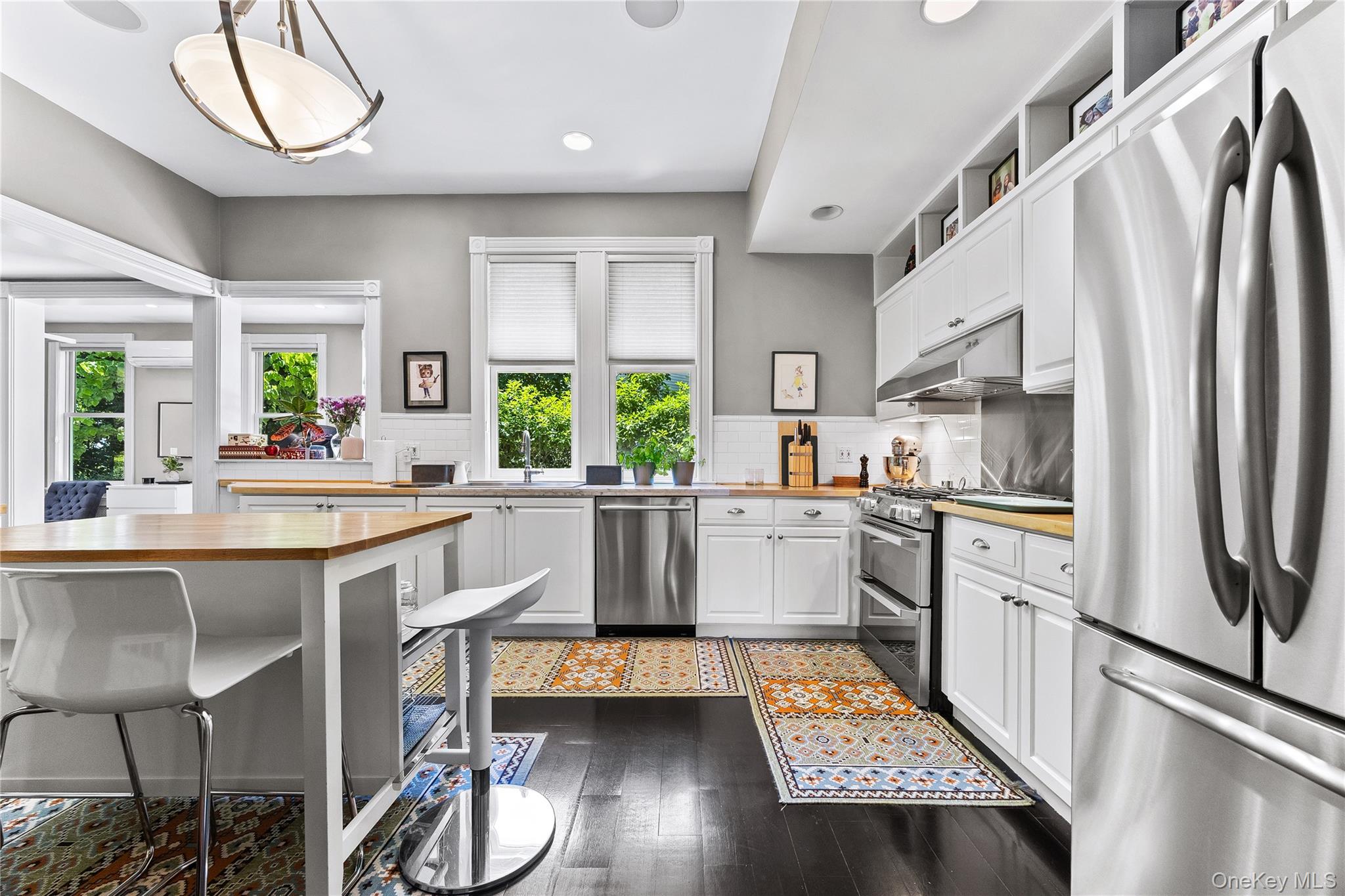 19 Howe Place Bronxville, NY 10708 - Photo 12 of 37 Kitchen featuring dark wood-finish flooring, white cabinetry, light wood-finish countertops, stainless steel appliances, and a white subway tile backsplash