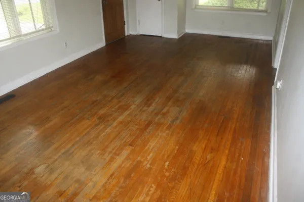 an empty room with wooden floor and windows