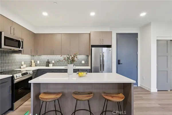 a kitchen with stainless steel appliances a dining table chairs and refrigerator
