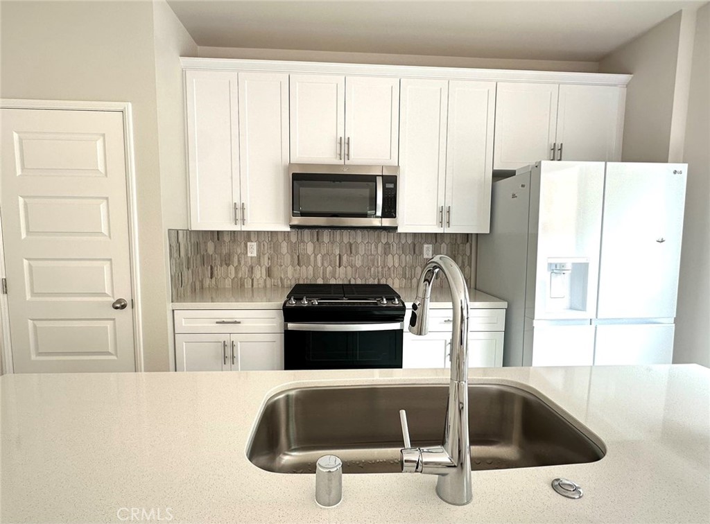 28221 Ashtree Street Temecula, CA 92591 - Photo 4 of 21 a kitchen with granite countertop a sink and a refrigerator