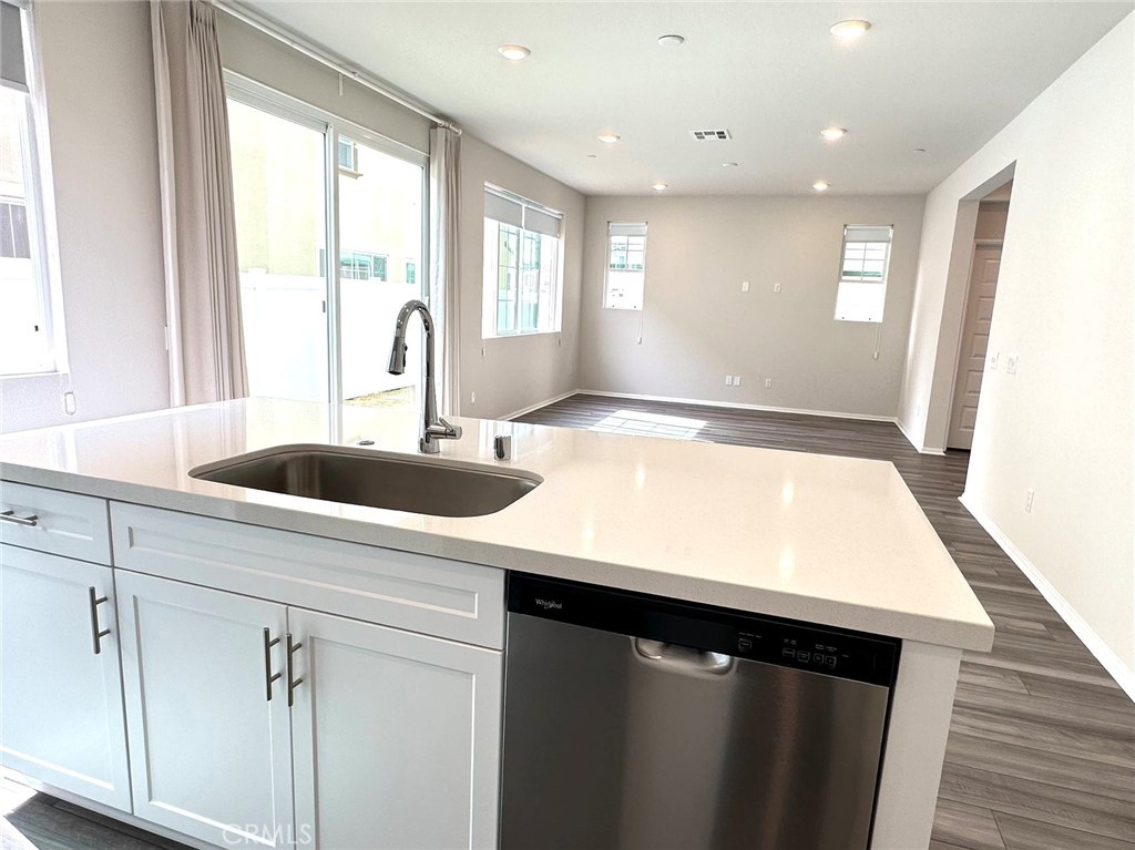 28221 Ashtree Street Temecula, CA 92591 - Photo 5 of 21 a kitchen with a sink dishwasher and white cabinets with wooden floor