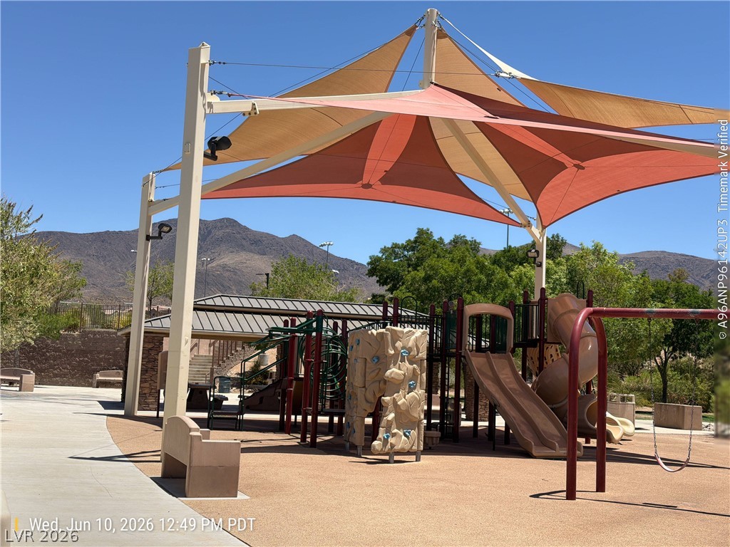 2388 Rue Bienville Way Henderson, NV 89044 - Photo 15 of 16 A well-equipped playground offers varied recreation under broad sunshades, framed by distant mountains.