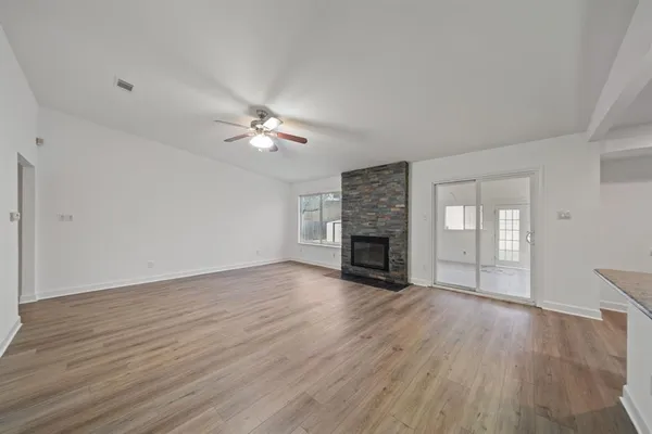 a view of an empty room with wooden floor fireplace and a window