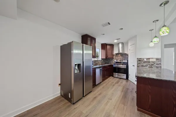a kitchen with granite countertop a refrigerator and a stove top oven