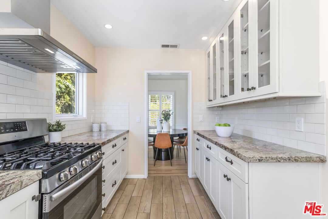 5967 Carpenter Avenue Valley Village, CA 91601 - Photo 12 of 32 a kitchen with stainless steel appliances granite countertop a stove and a white cabinets