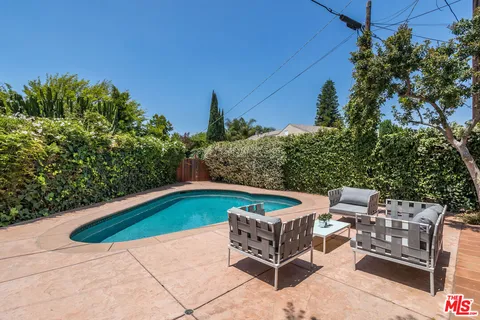 a backyard of a house with table and chairs under an umbrella