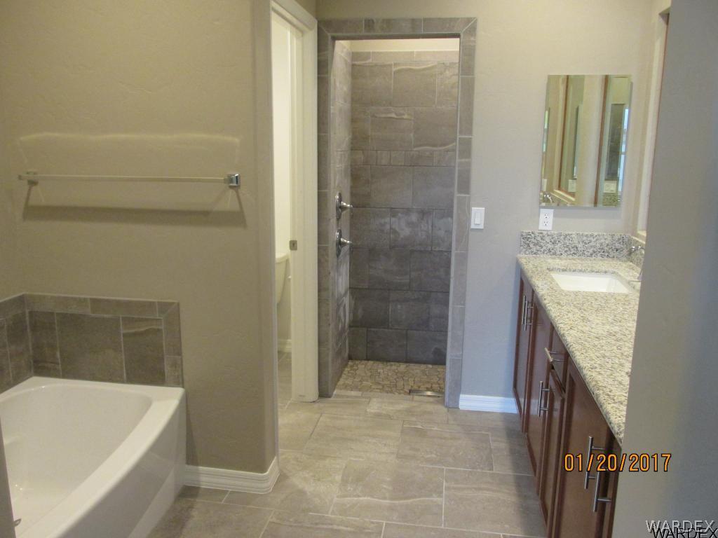 4276 East Cane Ranch Road Kingman, AZ 86401 - Photo 7 of 23 a bathroom with a granite countertop sink a bathtub and shower