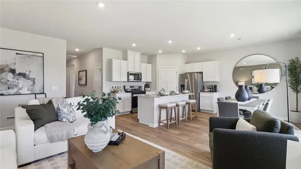 a living room with furniture kitchen view and a large window