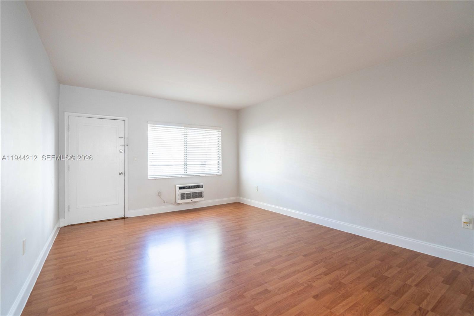 7315 Harding Avenue, Unit 16 Miami Beach, FL 33141 - Photo 5 of 13 an empty room with wooden floor and windows