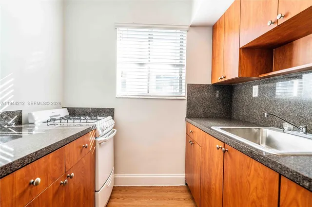 a kitchen view with granite countertop a sink and a window