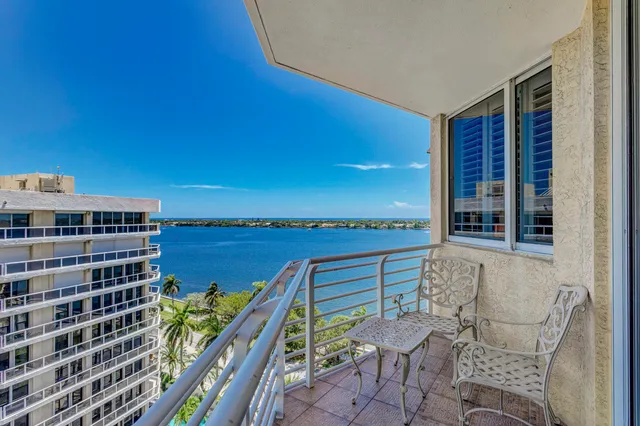 a balcony with table and chairs and potted plants
