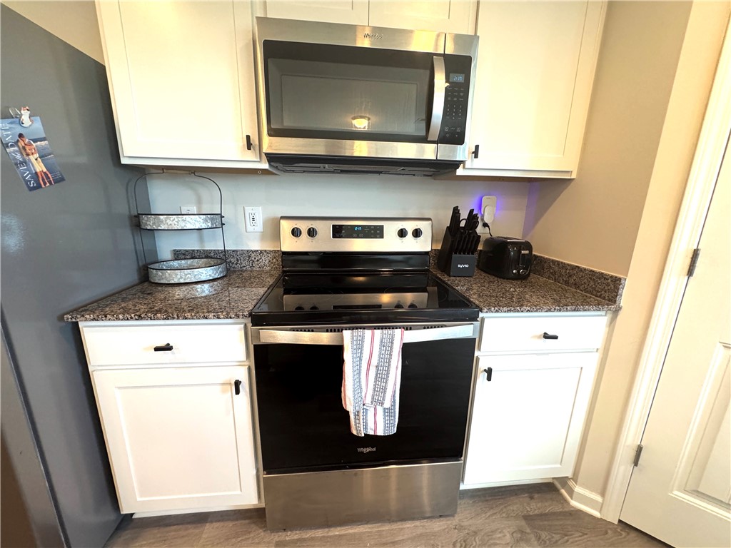 143 Adger Road Pendleton, SC 29670 - Photo 15 of 30 Granite countertops and white cabinetry flank the stainless steel range and built-in microwave.