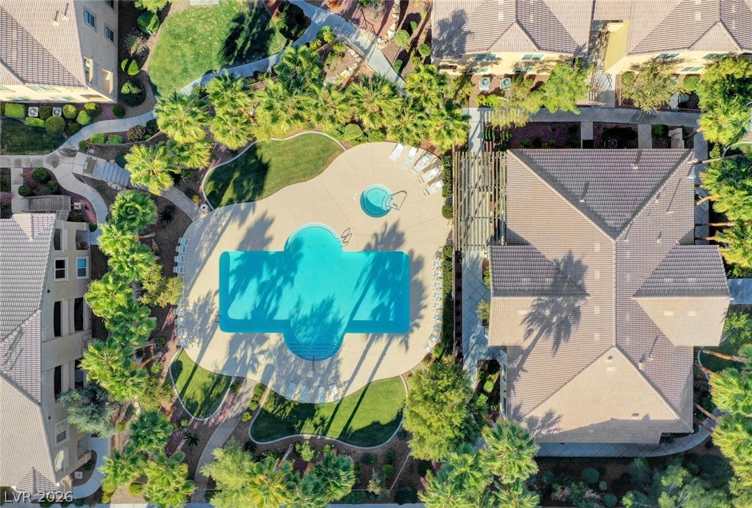 8985 South Durango Drive, Unit 2187 Las Vegas, NV 89113 - Photo 40 of 73 An aerial perspective reveals a serene community pool with an adjacent spa, encircled by lush landscaping and residential buildings.