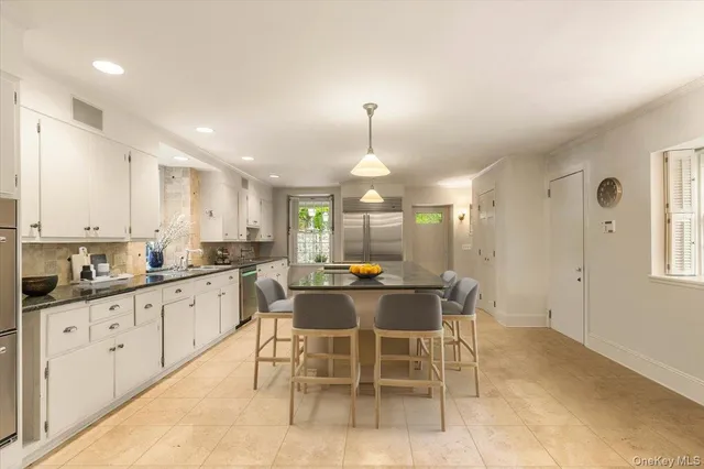 a kitchen with stainless steel appliances a dining table chairs and white cabinets